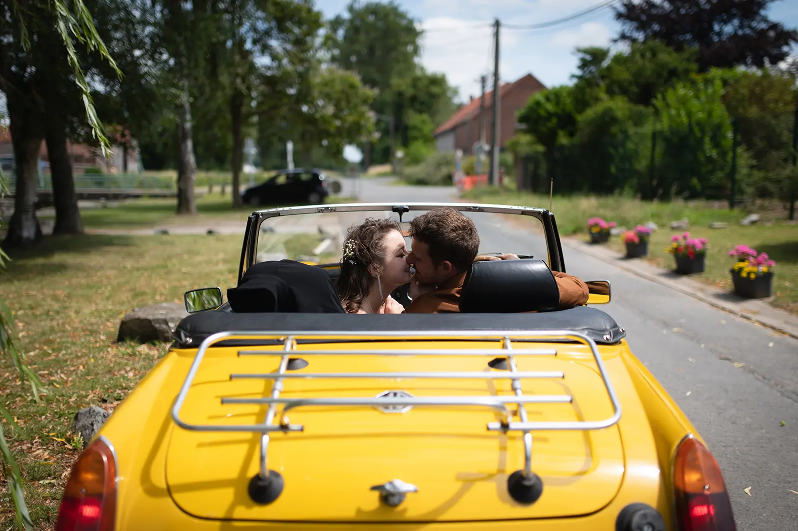 Mariés s'embrassant dans une voiture décapotable