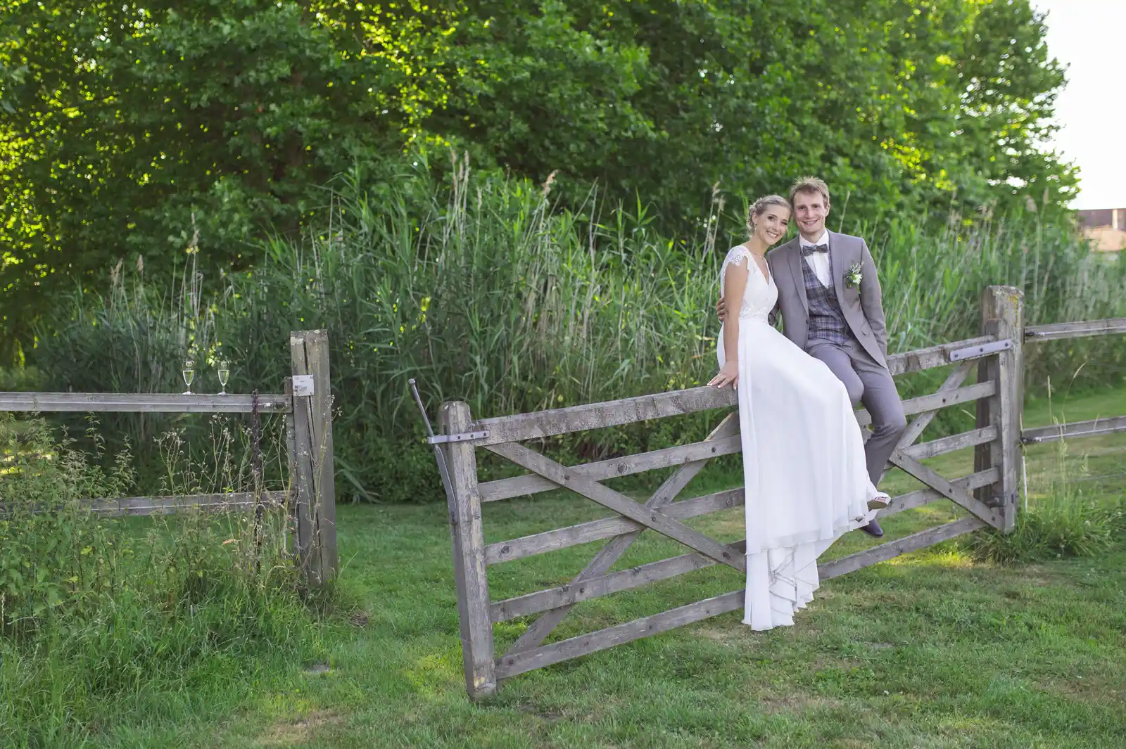 Mariés posant sur une barrière en bois